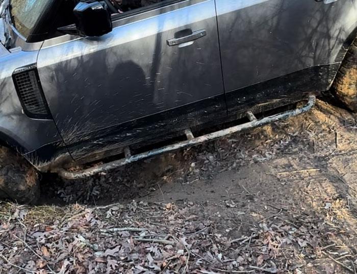 Land Rover Defender using rock sliders while offroading in the forest